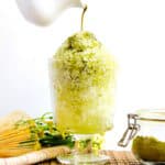 Homemade matcha syrup being pour of shaved ice.