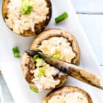 Miso crab stuffed mushrooms being cut in half with a knife, top down shot.