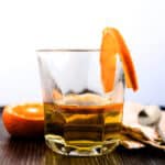 Orange whiskey soda served in a cocktail glass with a slice of orange on the rim.