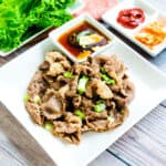 Pan fried Korean BBQ chadol brisket topped with green onions served with chadol sauce, top down view.