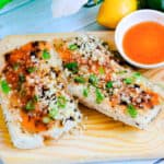 Pan seared sweet Thai chili mahi mahi served on a wooden serving board topped with green onions.