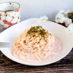 Tarako spaghetti served on a white plate topped with shredded seaweed.