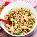 Asian style chicken stir fry served in a white bowl with a renge, an Asian style spoon.