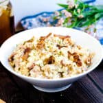 Bacon risotto made with rice served in a white bowl, side angle shot.