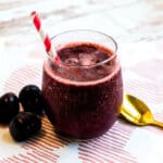 Homemade cherry slushie served in a glass with a straw.