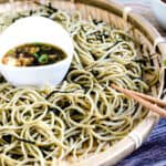 Japanese cold noodle soba made with edamame noodles being picked up with a pair of chopsticks.