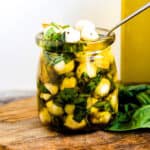 Marinated mozzarella balls served in a mason jar packed with fresh basil and garlic.