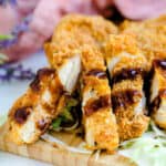 Air fryer Japanese chicken cutlet served over a bed of cabbage with kastu sauce drizzled over.