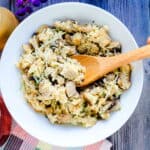 Chicken mushroom risotto made with cauliflower rice being picked up with a wooden spoon, top down shot.