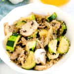 Garlic butter vegetable stir fry served in a white bowl topped with toasted sesame seeds.