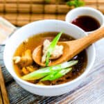 Japanese chicken soup being scooped up with a wooden spoon.
