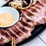 Japanese style grilled squid calamari sliced into rings served on a cast iron plate with a spicy mayo dipping sauce.