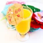 Tropical mango slush slushie in a cup served with a cocktail umbrella and straw.