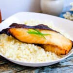 Japanese style miso marinated black cod gindara baked in the oven and severed over a bed of rice topped with slices of green onions.