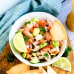 Shrimp Ceviche served in a white bowl with a side of lime wedge and baked low carb chips, top down shot.