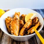 Japanese tebasaki chicken wings served in a white bowl with a wedge of lemon.
