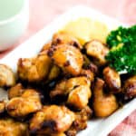 Air fried soy sauce chicken marinade served on a white plate with a wedge of lemon and fresh parsley.