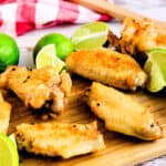 Crispy oven baked chili lime chicken wings served on a wooden serving board with extra pepper on side.
