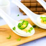 Japanese style deviled eggs topped with sliced jalapeno and chopped green onions served in a Japanese style renge spoon.