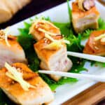 Japanese style seared pork belly being picked up with a pair of chopsticks.