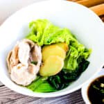 Japanese style pork hot pot shabu shabu with pork, napa, ginger, and bok choy in a white bowl.