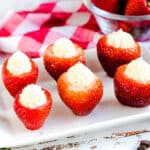 Cheesecake stuffed strawberries served on a white serving plate, side angle shot.