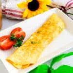 Japanese breakfast egg roll served on a white plate served with a fork.