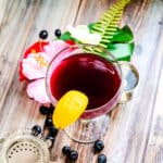 Berry flavored rum soda served in a cocktail glass with a wedge of lemon, top down view.