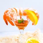 Shrimp cocktail served in a cocktail glass with healthy homemade shrimp cocktail sauce in the middle garnished with fresh parsley.