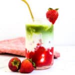 Strawberry matcha latte served in a glass cup with a gold straw.