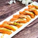 Japanese style salmon carpaccio sashimi in topped with green onions and sliced ginger served in a citrus soy sauce and sesame oil sauce.