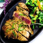 Pan seared ahi tuna steak served on a cast iron plate with a side of green salad, top down shot.