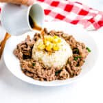Japanese beef pepper rice served on a plate with sauce being poured on.