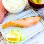 Japanese baked salmon served on a plate with a side of miso soup and rice.