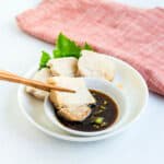 Pork belly being dipped into Asian style pork belly sauce.