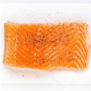 Salmon being seasoned.