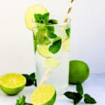 Mojito served in a glass with limes and fresh mint leaves.