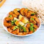 Baked old bay shrimp served on a plate topped with cilantro.