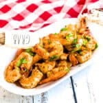 Pan fried Cajun shrimp being picked up with a tong.