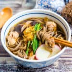 Japanese chicken noodle soup hot soba being picked up with chopsticks.