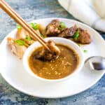 Grilled meat being dipped into Korean BBQ sweet dipping sauce.