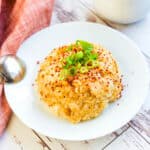 Spicy garlic rice served in a bowl topped with green onions.