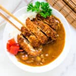 Chicken Katsu curry being picked with chopsticks.