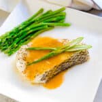 Miso butter Chilean seabass topped with green onions served on a white plate.