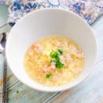 Crab egg drop soup served in a bowl topped with green onions.