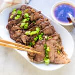 Japanese style pot roast sliced on a plate topped with green onions.