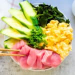 Japanese style sashimi tuna bowl being picked up with chopsticks.