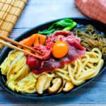 Beef sukiyaki being picked up with a chopstick.