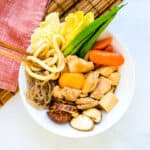 Chicken sukiyaki being picked up with a chopstick.