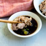 Shabu shabu meat being dipped into shabu shabu dipping sauce.